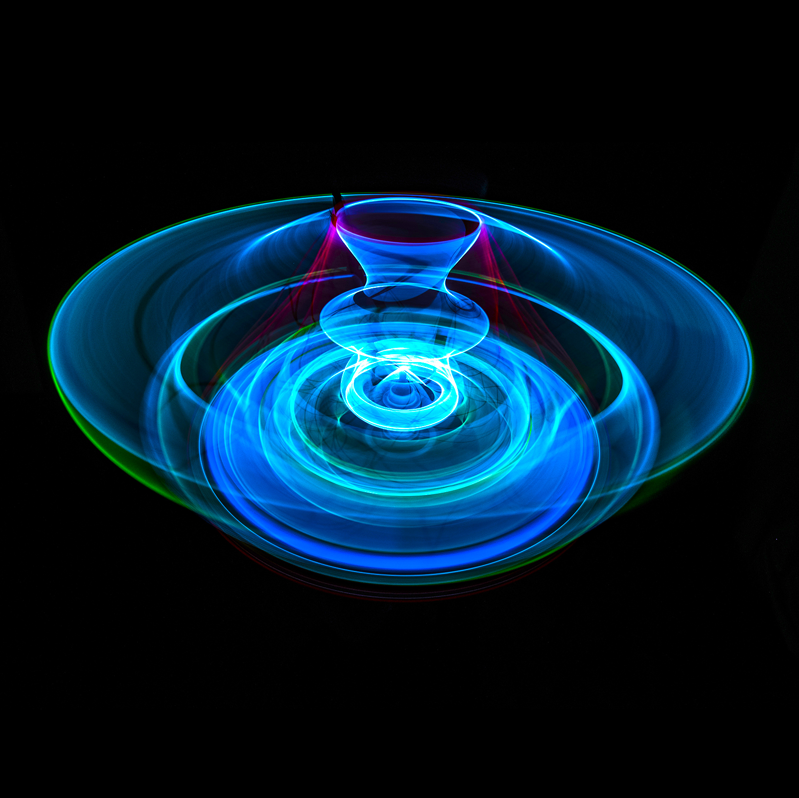 Layered rings of vivid blue and turquoise light form a wide wheel around a small central shape
