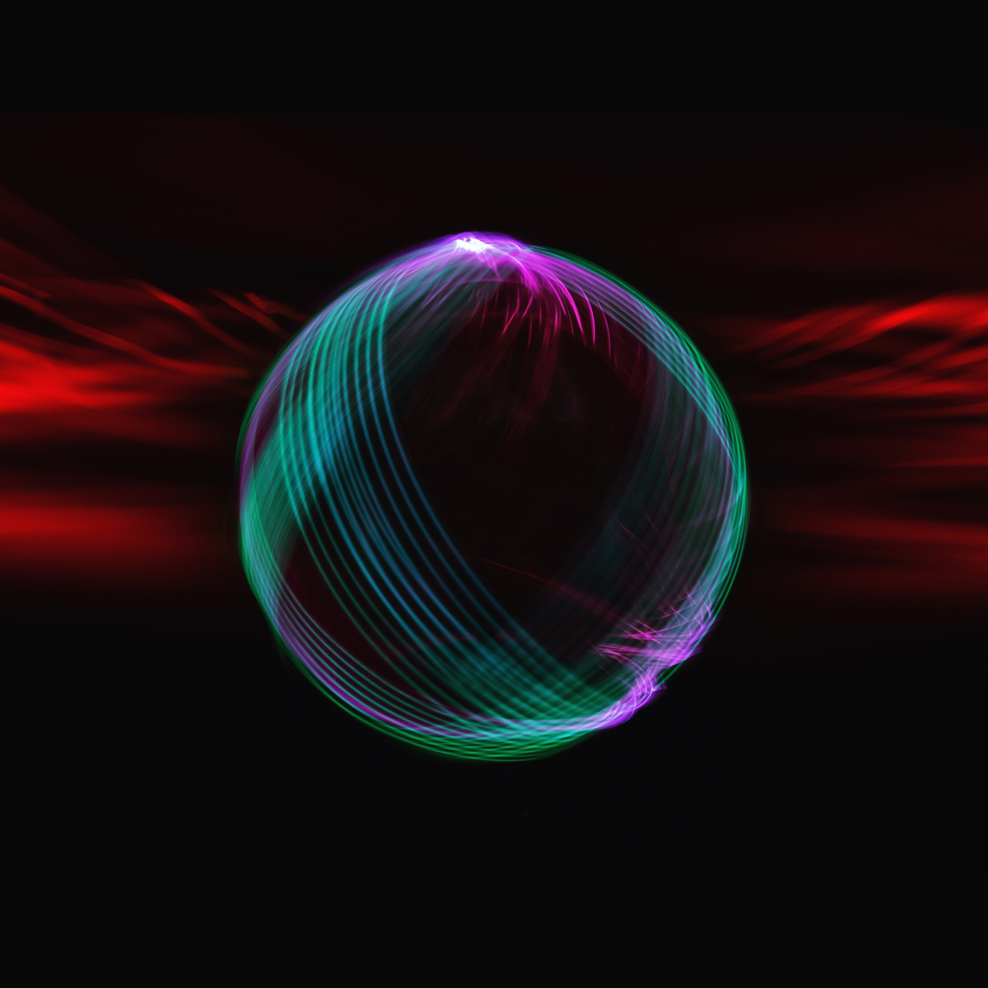 A red, turquoise and violet orb of light reflected across darkness