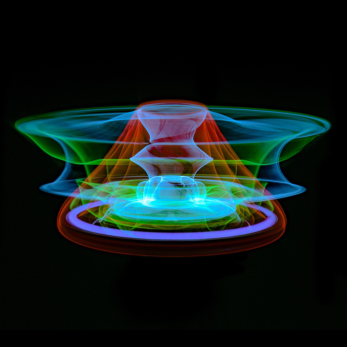 A wide, layered light form in green, blue, orange and violet